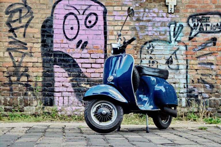 Moped på brostein foran grafittivegg.