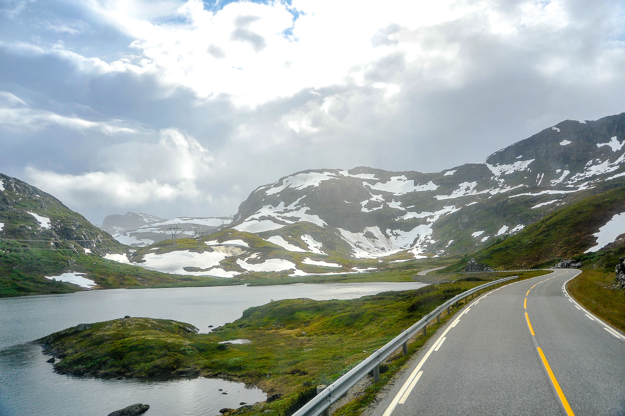 Smal veibane langs en fjor med fjell i bakgrunnen